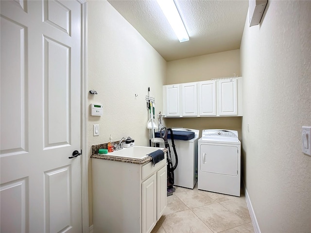 laundry room featuring washing machine and clothes dryer, sink, cabinets, a textured ceiling, and light tile patterned floors