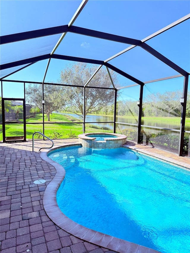 view of pool with an in ground hot tub, a water view, glass enclosure, and a patio area