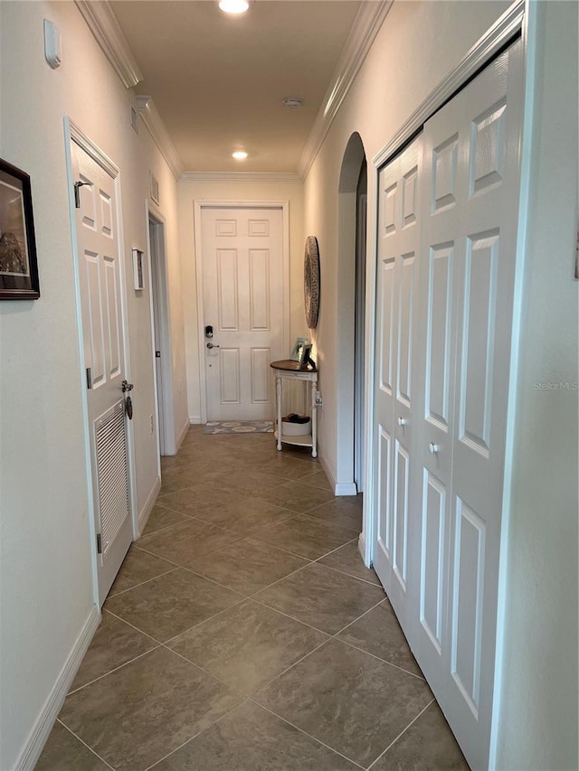 corridor featuring baseboards, arched walkways, ornamental molding, dark tile patterned floors, and recessed lighting