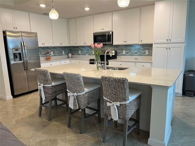 kitchen featuring appliances with stainless steel finishes, pendant lighting, white cabinetry, and a sink