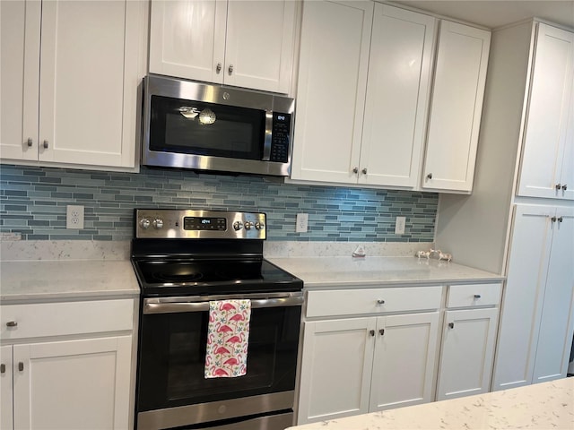 kitchen featuring white cabinets, light stone countertops, stainless steel appliances, and backsplash