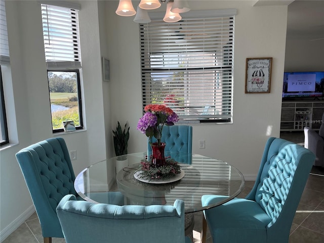 tiled dining space featuring a notable chandelier and baseboards