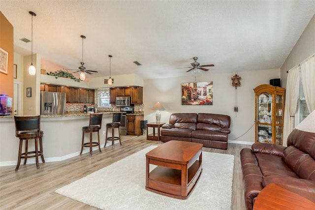 living room with ceiling fan, light hardwood / wood-style flooring, and a textured ceiling