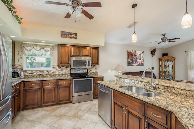 kitchen featuring sink, stainless steel appliances, tasteful backsplash, light stone countertops, and decorative light fixtures