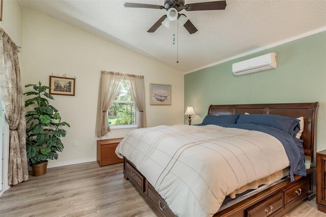 bedroom featuring light hardwood / wood-style floors, vaulted ceiling, a textured ceiling, and an AC wall unit