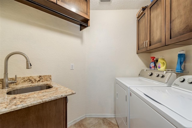 laundry area featuring sink, cabinets, separate washer and dryer, a textured ceiling, and light tile patterned floors