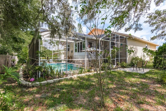 rear view of house featuring a fenced in pool, a patio area, and glass enclosure