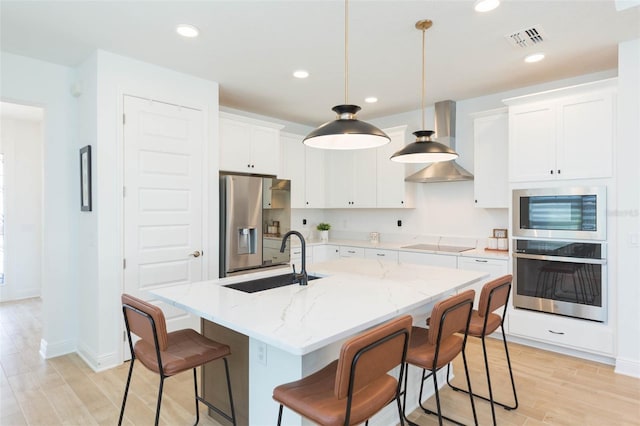 kitchen with pendant lighting, white cabinetry, sink, a kitchen island with sink, and stainless steel appliances