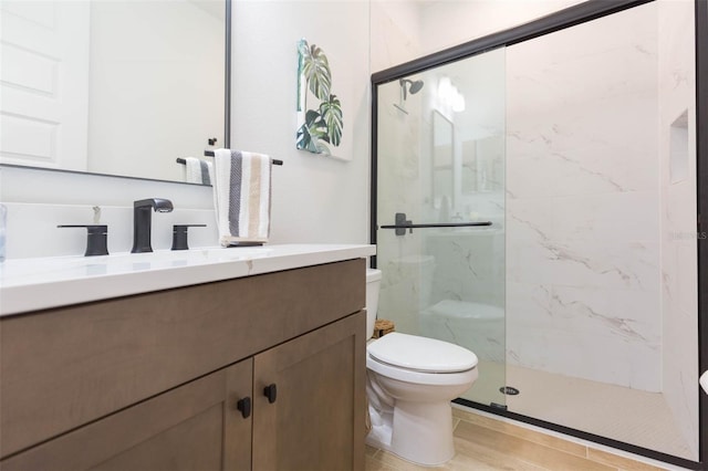 bathroom with an enclosed shower, vanity, and toilet