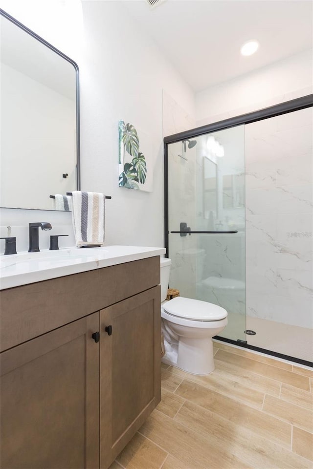 bathroom with vanity, an enclosed shower, and toilet