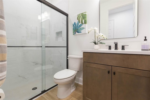 bathroom featuring hardwood / wood-style flooring, vanity, a shower with shower door, and toilet