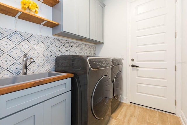 washroom with cabinets, sink, washer and dryer, and light hardwood / wood-style flooring