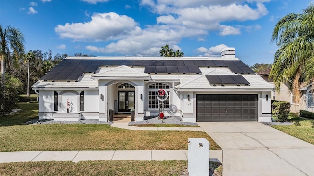 view of front of home featuring a garage, solar panels, and a front lawn