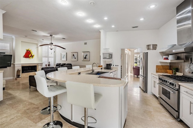 kitchen featuring appliances with stainless steel finishes, white cabinetry, sink, a kitchen bar, and a kitchen island with sink