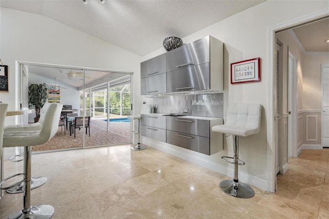 kitchen with ornamental molding, vaulted ceiling, decorative backsplash, and gray cabinetry