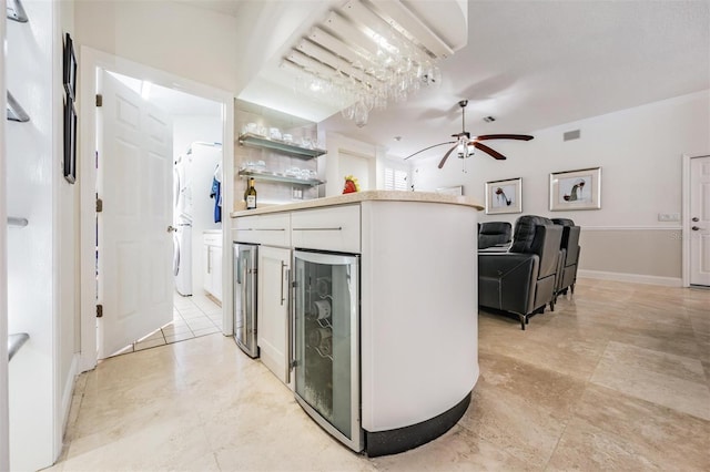 kitchen with ceiling fan, beverage cooler, and white cabinets