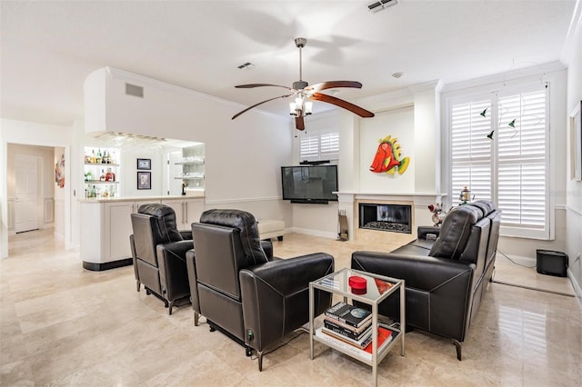 living room featuring crown molding, ceiling fan, and indoor bar