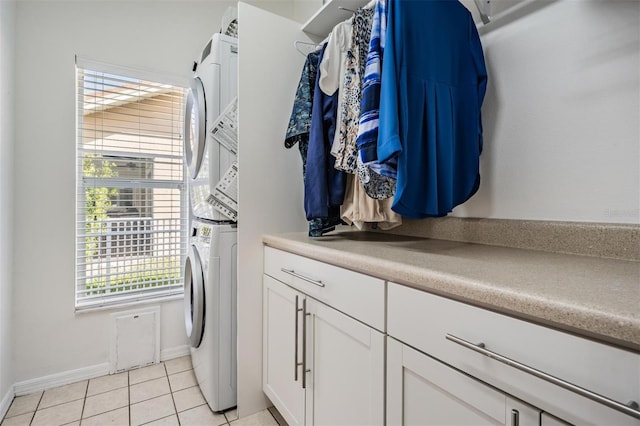 laundry room with cabinets, stacked washing maching and dryer, and light tile patterned floors