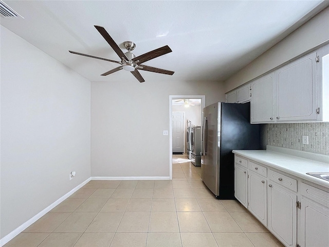 kitchen with white cabinetry, stainless steel fridge, decorative backsplash, light tile patterned floors, and ceiling fan