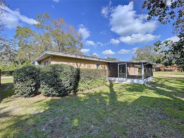 rear view of house featuring a sunroom and a lawn