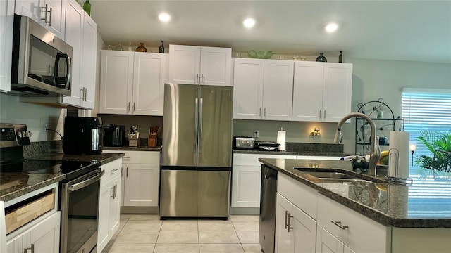 10854 Sage Canyon Dr, Riverview, FL 33578 - kitchen with light tile patterned floors, stainless steel appliances, a sink, white cabinetry, and dark stone countertops