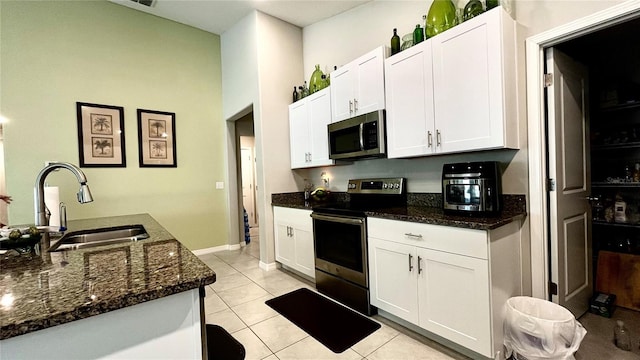 10854 Sage Canyon Dr, Riverview, FL 33578 - kitchen with light tile patterned floors, a sink, white cabinetry, appliances with stainless steel finishes, and dark stone countertops