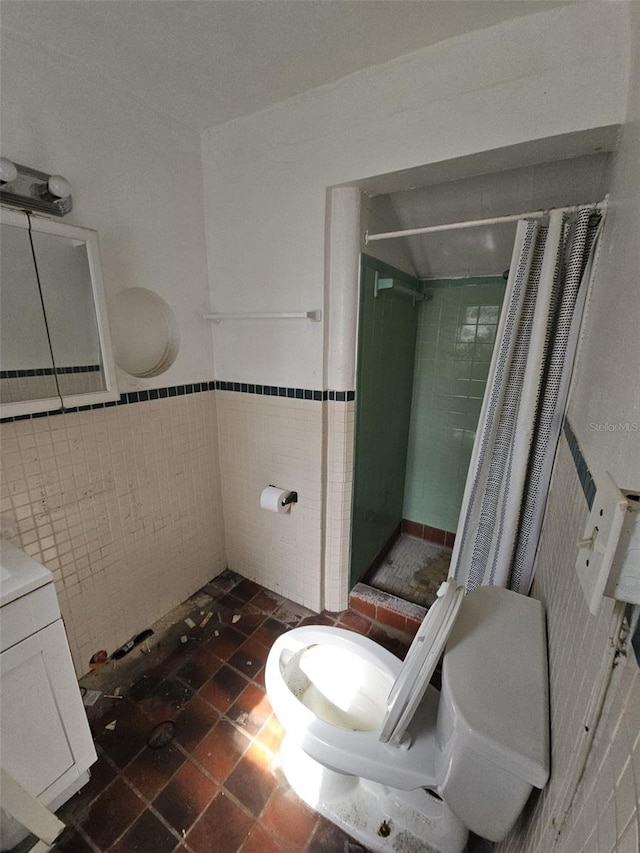 bathroom featuring walk in shower, vanity, toilet, and tile walls