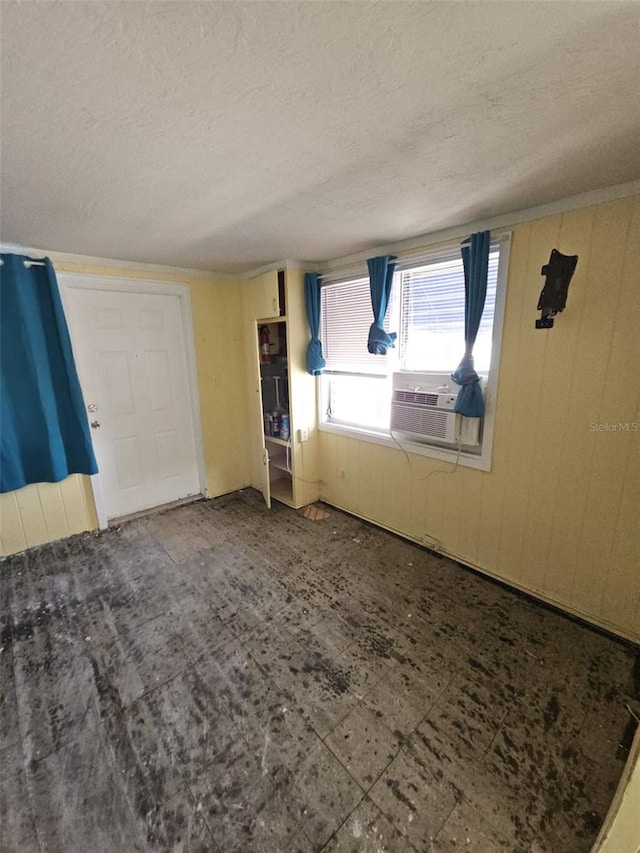 unfurnished room featuring wooden walls and a textured ceiling