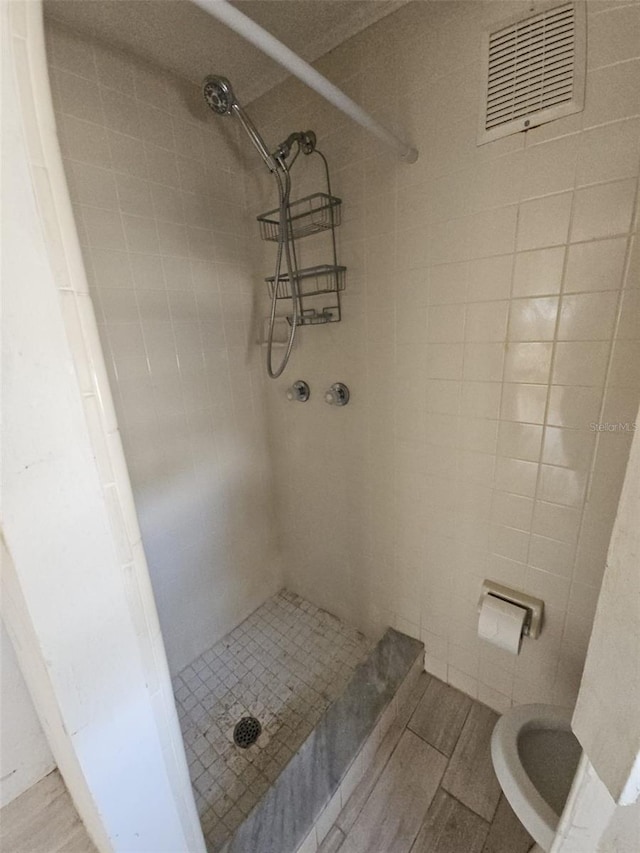 bathroom with tiled shower, toilet, and tile walls