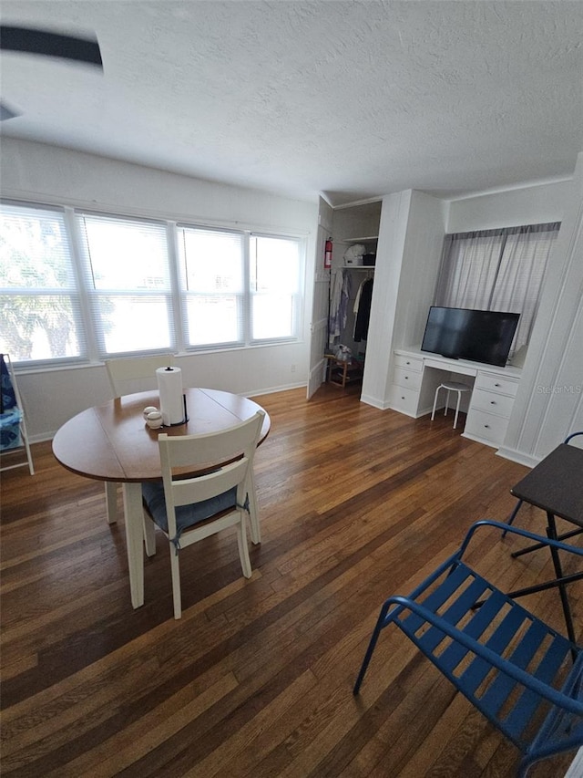 dining space with dark hardwood / wood-style flooring, built in desk, and a textured ceiling