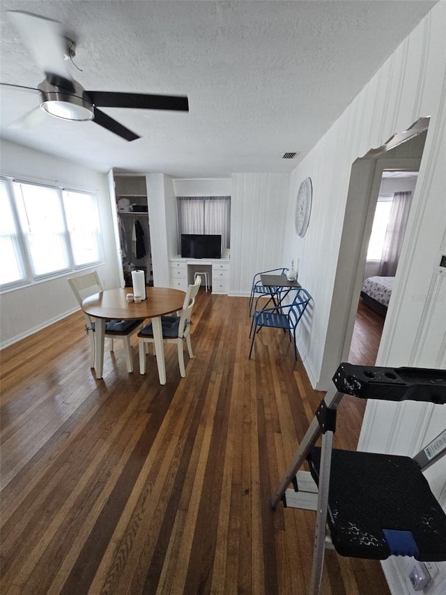 dining area featuring ceiling fan, dark hardwood / wood-style floors, and a textured ceiling