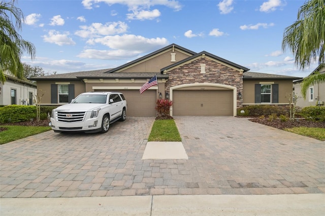 view of front of property with a garage, stone siding, decorative driveway, and stucco siding