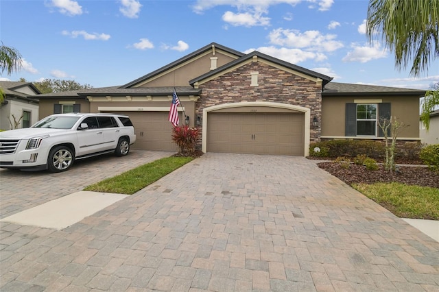 ranch-style home with stone siding, decorative driveway, an attached garage, and stucco siding