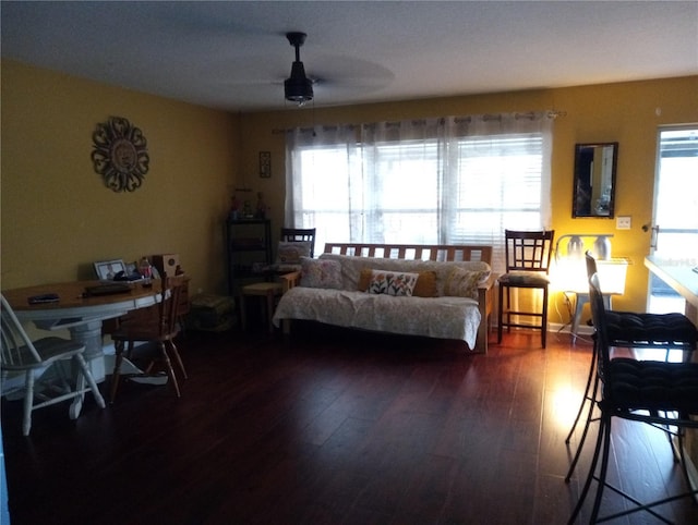 living area featuring a healthy amount of sunlight, a ceiling fan, and dark wood-style flooring