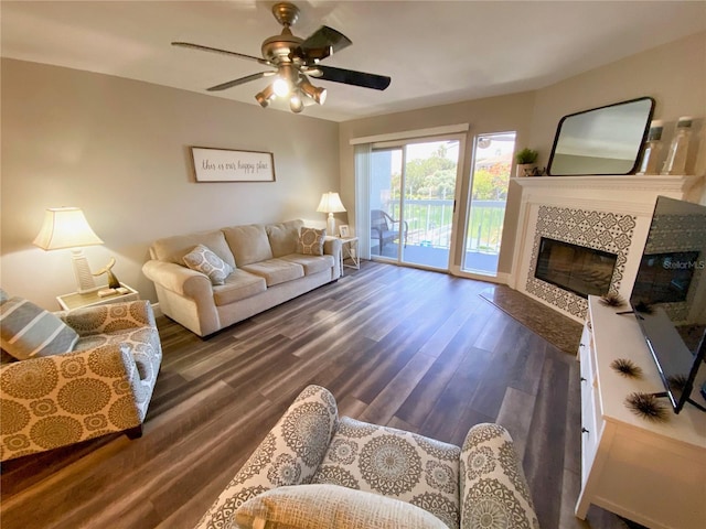 living room featuring dark wood-type flooring, a tile fireplace, and ceiling fan