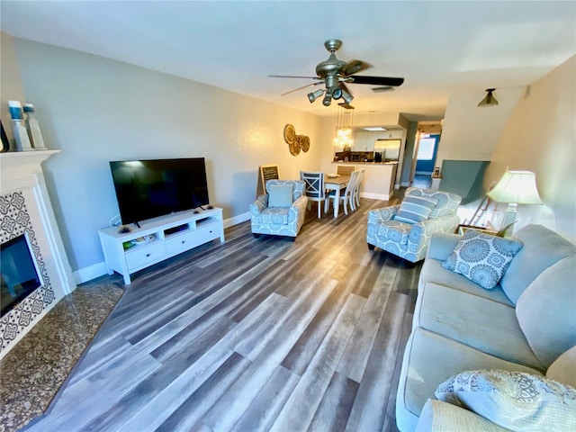 living room featuring hardwood / wood-style flooring, a tile fireplace, and ceiling fan