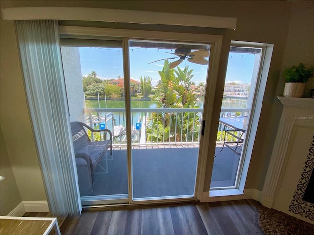 doorway to outside with a water view, dark wood-type flooring, and ceiling fan