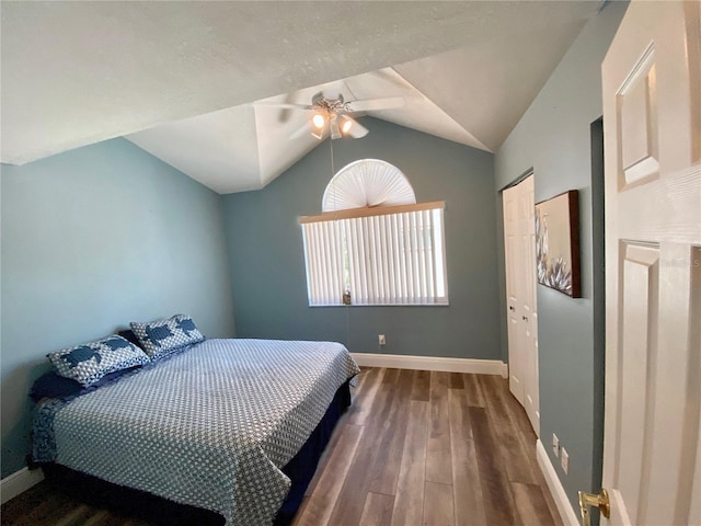 bedroom with vaulted ceiling, dark hardwood / wood-style floors, ceiling fan, and a closet