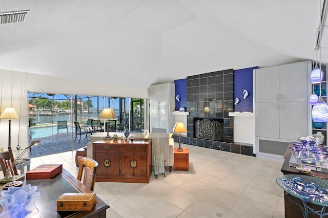 tiled living room featuring a tile fireplace, a water view, and high vaulted ceiling