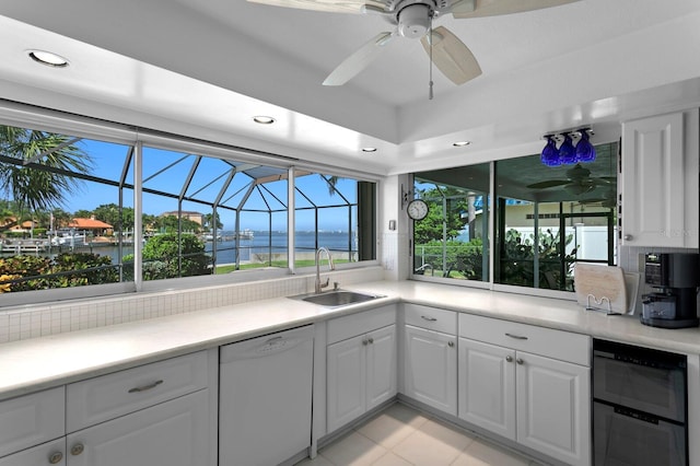 kitchen with a water view, white dishwasher, sink, and white cabinets