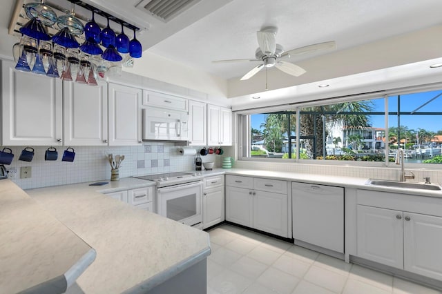 kitchen with backsplash, white appliances, sink, and white cabinets