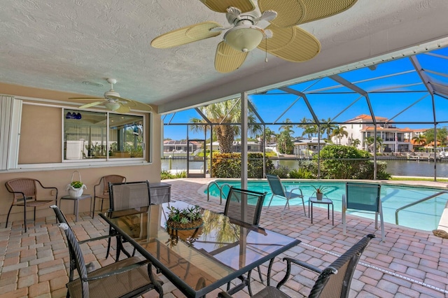 exterior space with a water view, glass enclosure, and a patio area