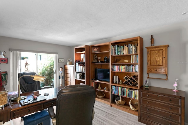 office with light hardwood / wood-style floors and a textured ceiling