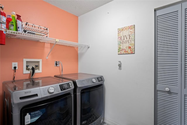 laundry area with washing machine and clothes dryer and a textured ceiling