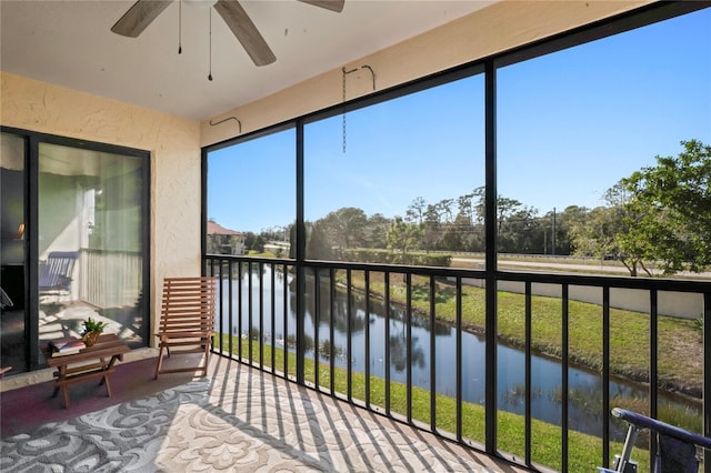 sunroom / solarium with ceiling fan and a water view