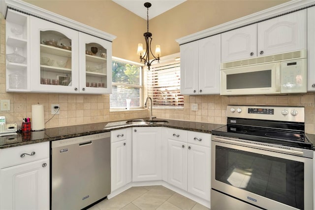 kitchen with white cabinets, stainless steel appliances, sink, and dark stone countertops