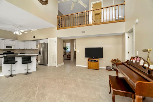 living room with a towering ceiling and ceiling fan