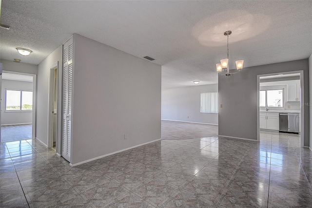 unfurnished room featuring a textured ceiling, tile patterned floors, and a chandelier