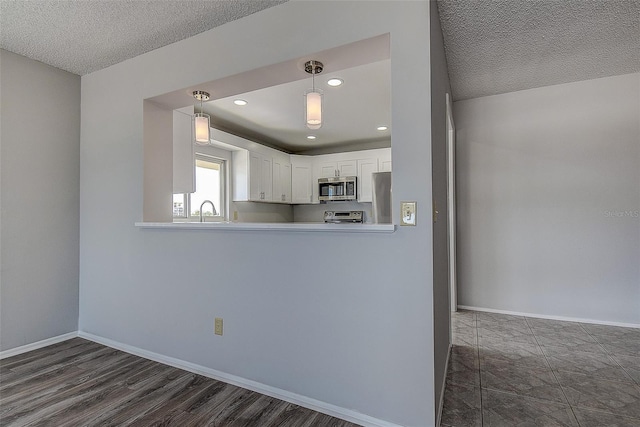 kitchen with sink, appliances with stainless steel finishes, a textured ceiling, white cabinets, and kitchen peninsula