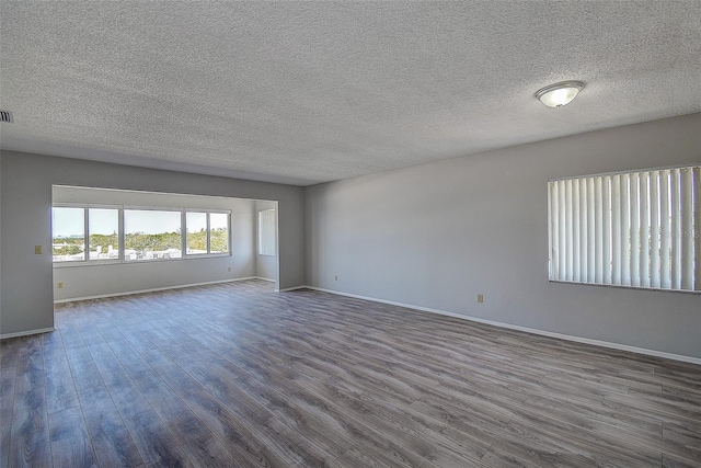 unfurnished room with dark wood-type flooring and a textured ceiling